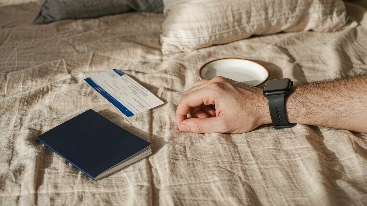 Smartwatch on a wrist beside a passport and boarding pass