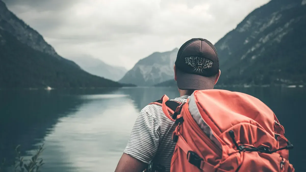 Hiker with a backpack looking at misty mountains