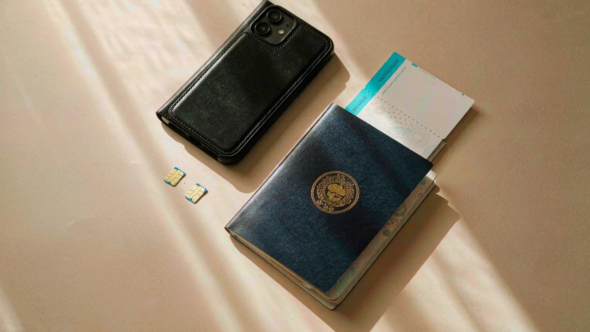 Travel desk flat-lay with phone, passport, SIM cards and boarding pass