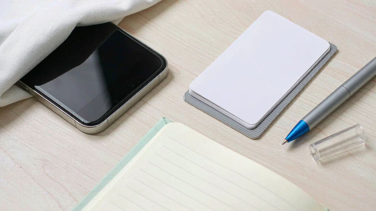 Flat-lay of a phone with prepaid cards, pen and notebook