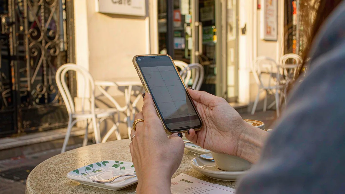 Traveler using an iPhone with a travel eSIM at a cafe abroad